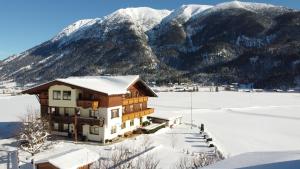 ein Haus im Schnee mit Bergen im Hintergrund in der Unterkunft Frühstückspension Seeblick in Achenkirch