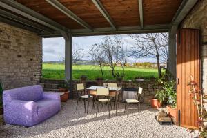 a patio with a purple couch and a table and chairs at Monolocale di Campagna - LePietreBnB in Pietrelcina