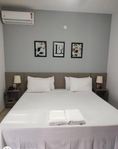 a bedroom with a white bed with two towels on it at Shellter Hotel in Holambra