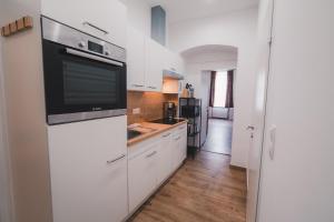 a kitchen with white cabinets and a large appliance at Renovated Apartment close to first district in Vienna