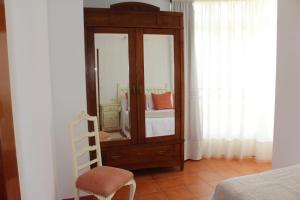 ein Schlafzimmer mit einer Kommode mit einem Spiegel und einem Stuhl in der Unterkunft APARTAMENTO AROSA in Vilanova de Arousa