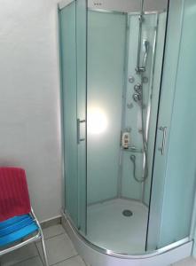 a glass shower with a red chair in a bathroom at JackTavern - Auberge de Jeunesse in Pointe-Noire