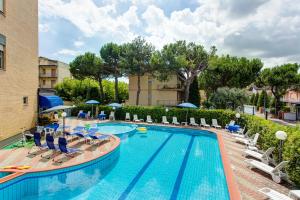a large swimming pool with chairs and umbrellas at Hotel Real in Cervia