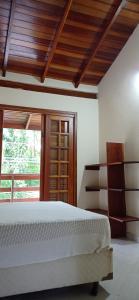 a bedroom with a white bed and a window at Casa dos Coqueiros Praia de Camburi, condomínio in Camburi