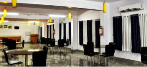 une chambre avec des chaises et des tables noires et une chambre avec des fenêtres dans l'établissement MADHU MAMATA HOTEL, à Tarapith