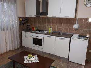 cocina con armarios blancos, fregadero y mesa en Biljevina, en Saborsko