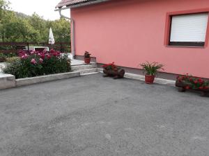 una casa rosa con macetas y flores en Biljevina, en Saborsko