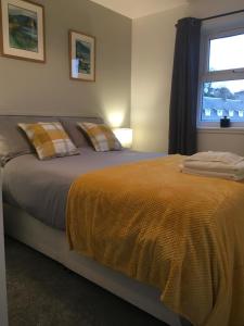 a bedroom with a bed with an orange blanket and a window at Cosy cottage with sea views close to local shops. in Lamlash