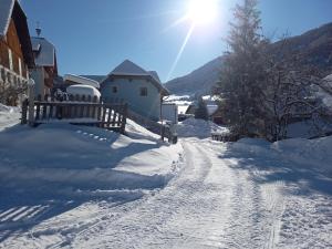 a snow covered road with a fence and a house at Hansalagut in Mauterndorf