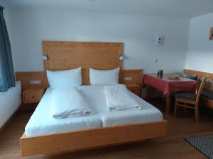 Schlafzimmer mit einem Bett mit einem Kopfteil aus Holz und einem Tisch in der Unterkunft Pension Appartementhaus Bergland in Biberwier