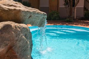 a water fountain in a pool with a rock at Pousada Nanai in Foz do Iguaçu