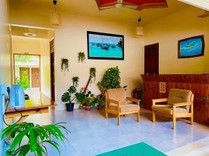 a living room with chairs and a tv on the wall at Thoddoo Retreat Grand in Thoddoo