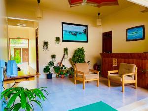 Thoddoo Retreat Grand في ثودو: غرفة معيشة مع كراسي وتلفزيون على الحائط