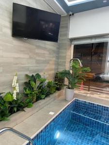 a swimming pool with a tv on a wall with plants at Hotel Andy in Atacames