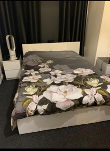 a bed with a blanket with white flowers on it at Belsize Park Boutique Accommodation in London