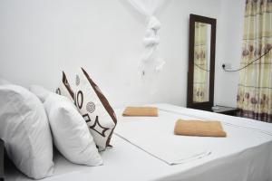 a white bed with white pillows at Sigiri Rock Side Home Stay in Sigiriya