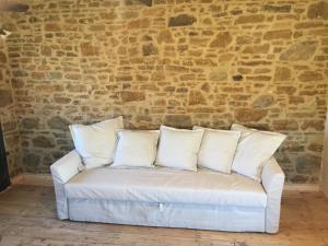 a white couch with four pillows in front of a brick wall at Lemnian house in Portiano in Pedhinón