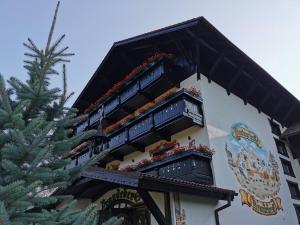 a building with balconies with flowers on them next to a christmas tree at Brandeberg Pension & Restaurant in Bran