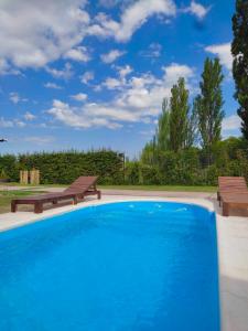 a large swimming pool with two benches in a yard at Chalet La Gringa in San Rafael