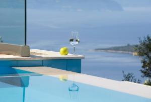 een glas wijn op een tafel naast een zwembad bij Heavenly Heights Villas in Évyiros