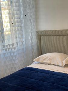 ein Schlafzimmer mit einem Bett mit einer blauen Decke und einem Fenster in der Unterkunft Alexandre in Nizza
