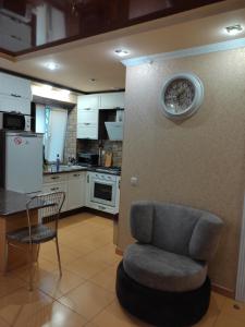 a kitchen with a chair and a clock on the wall at Comfortable Apartment in Kremenchuk