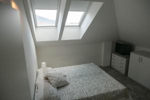 a white bedroom with a bed and two windows at Residenza Nam in Alassio