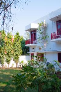 a white building with red balconies and trees at Falcon guest house in Bharatpur