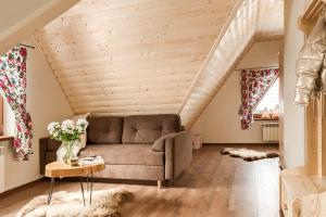 a living room with a couch and a wooden ceiling at Apartamenty VILLA SKI-BÓWKI in Zakopane