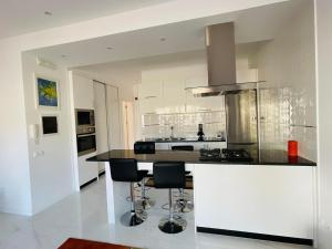 a kitchen with a counter and stools in it at Duarte Apartments - Laginha in Mindelo
