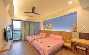 sypialnia z 2 łóżkami, biurkiem i oknem w obiekcie 澎湖寶貝民宿 w mieście Huxi
