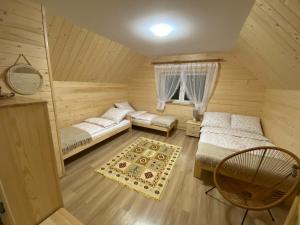 a attic bedroom with two beds and a chair at Domki pod Grapą in Trybsz