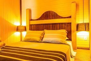 a bedroom with a wooden bed with yellow and white pillows at Pousada Casa do Oscar in Governador Celso Ramos