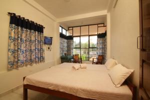 a bedroom with a bed with white sheets and a window at Royal Holidays in Alleppey