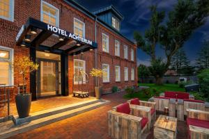 a hotel exterior with tables and chairs in front of a brick building at Hotel Achterum Greetsiel in Greetsiel