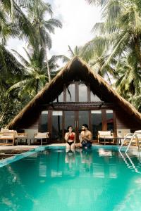 dos personas sentadas en el agua en una piscina en Coconut Escapes, en Kurunegala