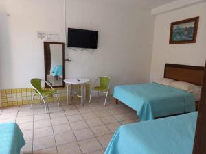 a room with two beds and a table and a mirror at Airport Sleepy Inn in Cancún