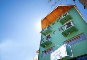 a green building with balconies on the side of it at Pousada Araucária in Campos do Jordão