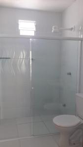 La salle de bains est pourvue de toilettes et d'une douche en verre. dans l'établissement Suíte em Japaratinga com Vista do Mar, à Japaratinga