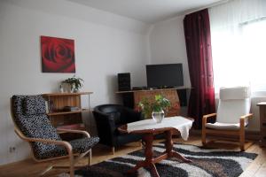 Apartment in Chemnitz, Ebersdorfer Wald في شيمنيتز: غرفة معيشة مع طاولة وكراسي وتلفزيون