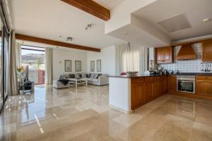 a kitchen with wooden cabinets and a living room at Sunset Villa in La Playa de Tauro