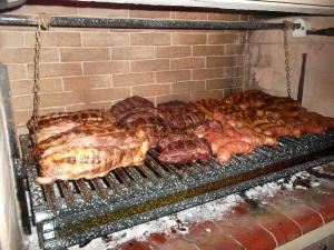 a grill with meat and other food on it at LA CASA DE COCO ALOJAMIENTO TURÍSTICO in Dina Huapi