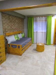a bedroom with a bed with green curtains and a table at LA CASA DE COCO ALOJAMIENTO TURÍSTICO in Dina Huapi +10 photos