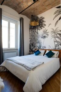 una camera da letto con un grande letto bianco con cuscini blu di la polveriera, appartamenti eleganti e luminosi vicino al Colosseo a Roma