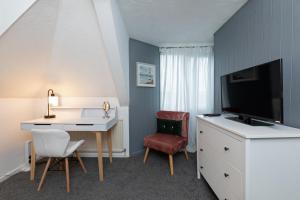a hotel room with a desk and a tv and a table at Spacious apartment with free parking in Weymouth