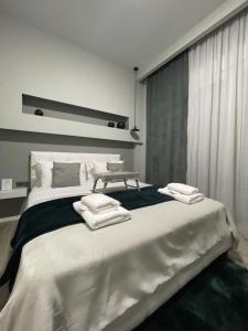 - une chambre avec un grand lit et des serviettes dans l'établissement Calma Suite (Cielo suites), à Kavala