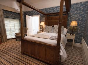 a bedroom with a canopy bed and blue wallpaper at The Bear, Cowbridge in Cowbridge