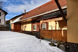 a house with snow on the ground in front of it at Penzion Crystal in Nová Lesná