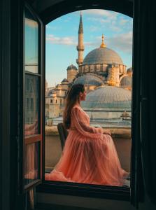 a woman in a pink dress looking out a window at Mest Hotel Istanbul Sirkeci in Istanbul