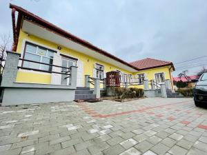 a yellow house with a car parked in front of it at Casa Benke Ház in Covasna